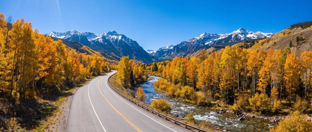 A two-lane road through a Colorado mountain valley in autumn